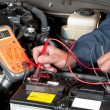 Auto mechanic checking car battery voltage